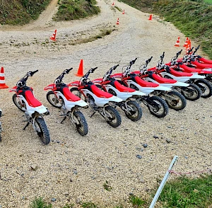 Row of parked red Honda off-road bikes with traffic cones on the gravel beginners track