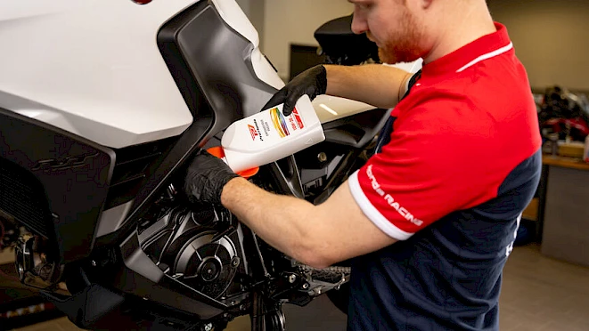 Honda mechanic filling genuine Honda engine oil into a motorcycle – genuine parts with warranty