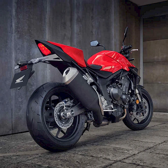 Red Honda CB1000 Hornet naked bike from behind in front of a concrete wall – category A motorcycle