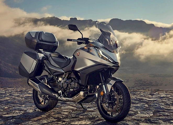 Grey Honda NT1100 with panniers and top box in front of cloud-covered mountains – category A tourer