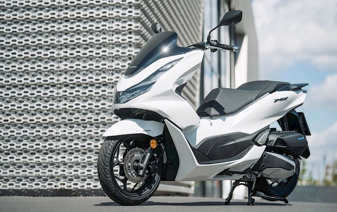 White Honda PCX125 DX in front of a perforated metal facade – motorcycle category A1 with automatic and storage space