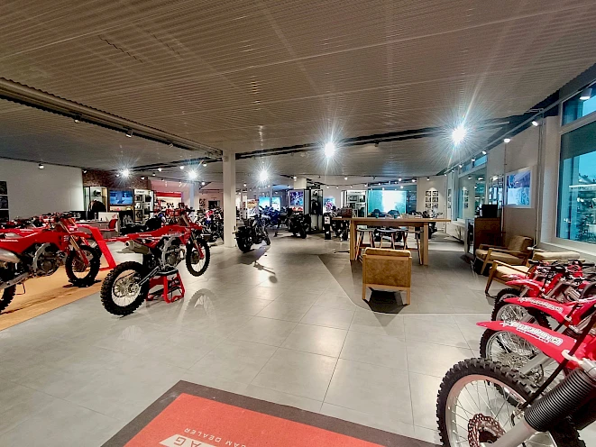 Motorcycle dealership Honda Motorrad Zürich – showroom with red Honda CRF bikes, display models and lounge area