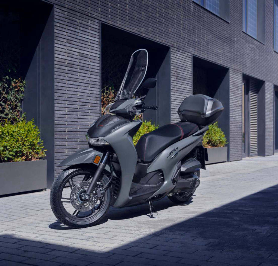 Scooter Honda SH150 en ville avec accessoires d’origine : top case et bulle